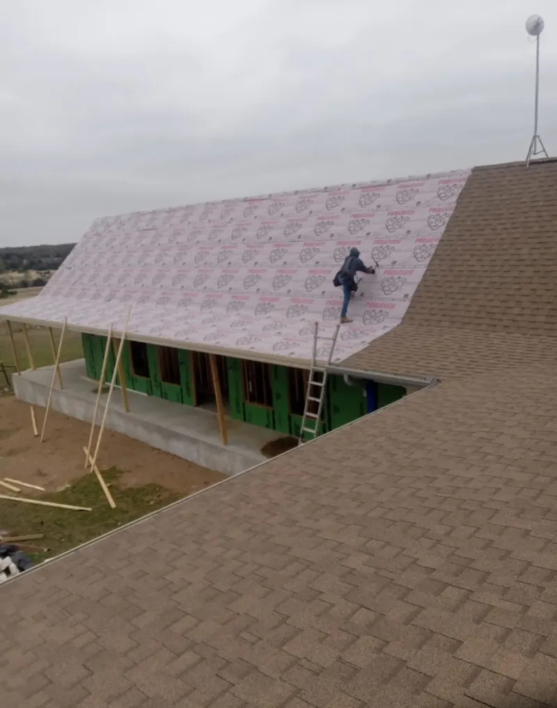 Worker preparing underlayment for a metal roof installation in Willoughby